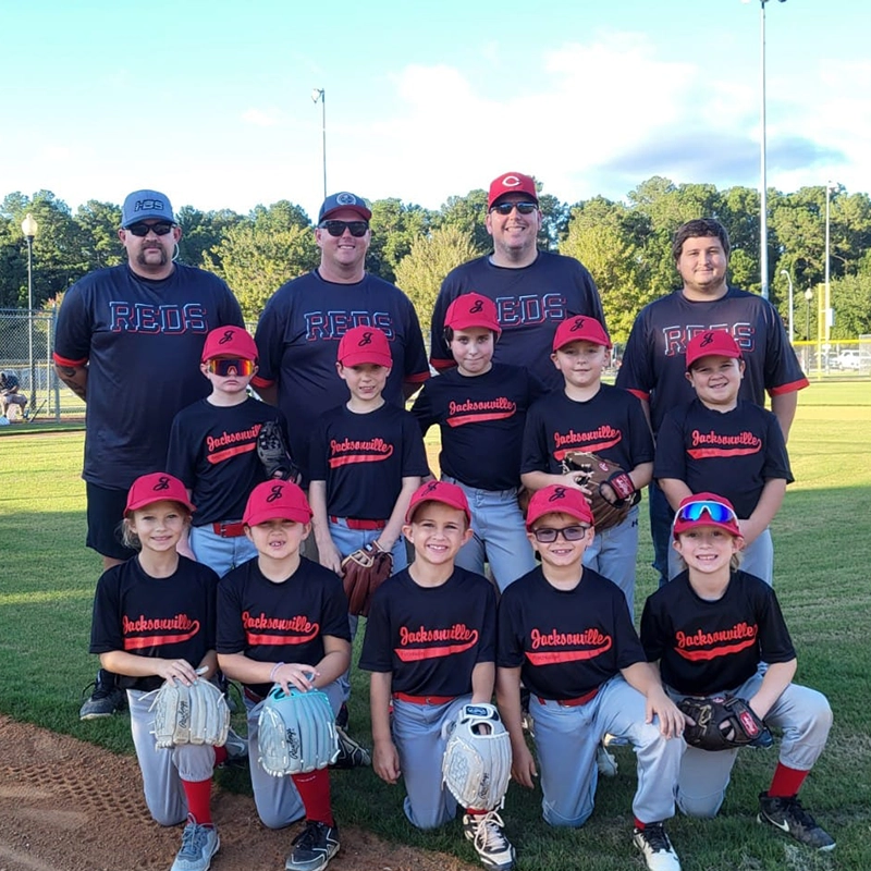 Chris Schulte and three other adults alongside a Little League baseball team