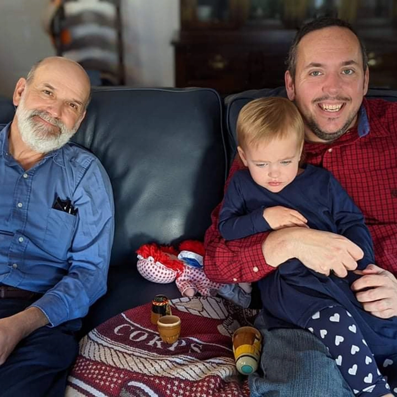 Chris Schulte sitting on a couch with his son and dad